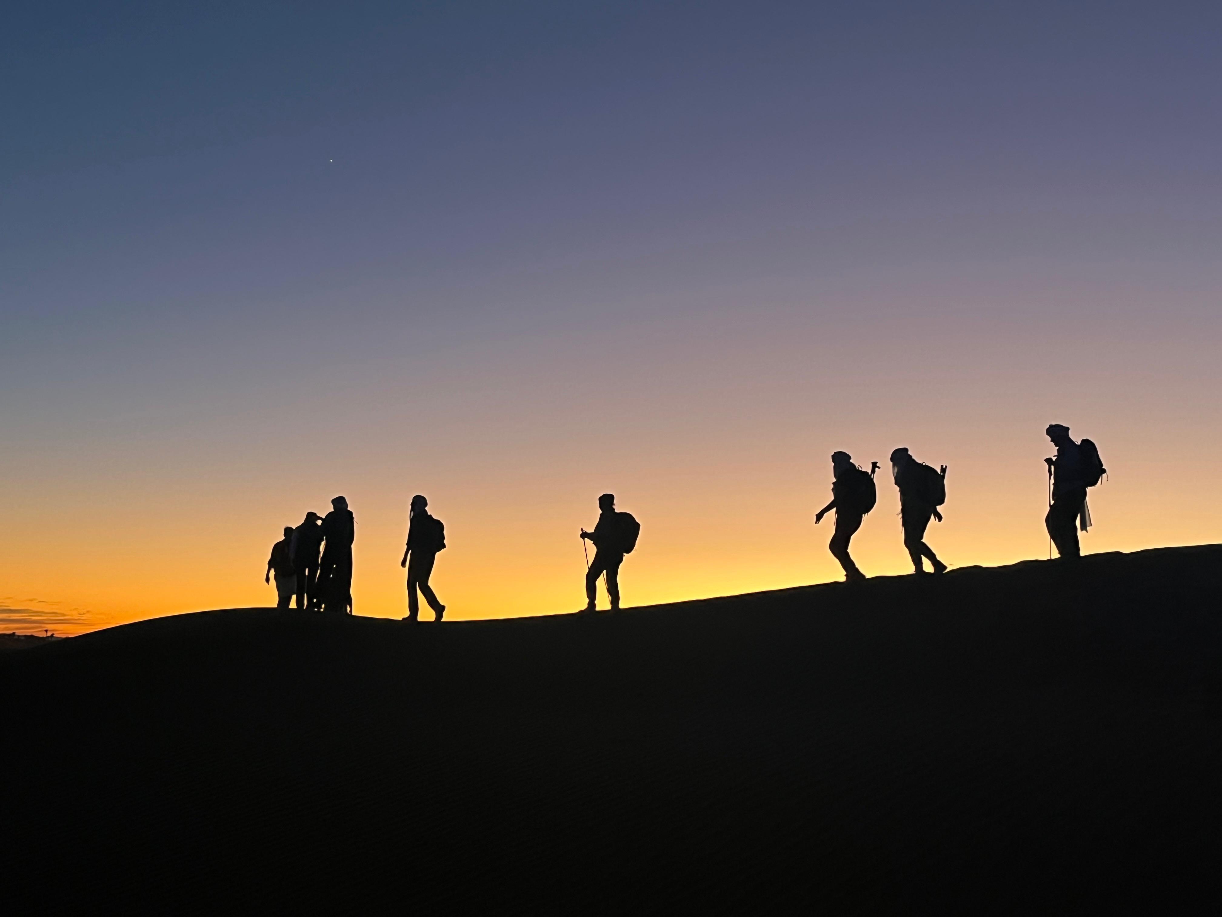 Trekkinggruppe in der Sahara bei Sonnenuntergang